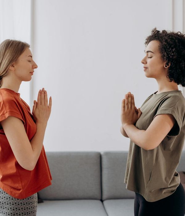 Woman in a calm yoga pose in a softly lit room.